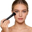 A woman is using a flat-top foundation brush.