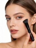 A woman is using a black angled foundation brush.