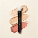 Sophienia makeup brush with white bristles and black handle on beige background with powder and liquid foundation swatches