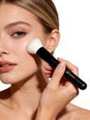 Woman applying powder to cheek with sophienia white bristle makeup brush featuring black handle