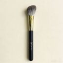 Sophienia makeup brush with soft gray bristles, gold ferrule, and black handle on beige background