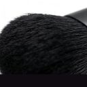 Soft black makeup powder brush with dense bristles shown in close-up macro detail against white background