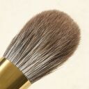 Soft natural hair makeup brush with gold ferrule, showing dense rounded bristles in gray-brown tones