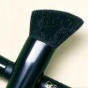 Angled contour makeup brush with dark bristles and black handle featuring gold sophienia logo on cream background